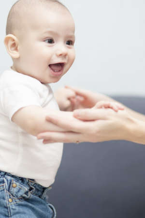 loverly portrait of a newborn toddler on a sofa holding mother's handsの写真素材