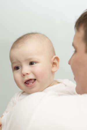little newborn son sitting over a father's shoulder and looking backの写真素材