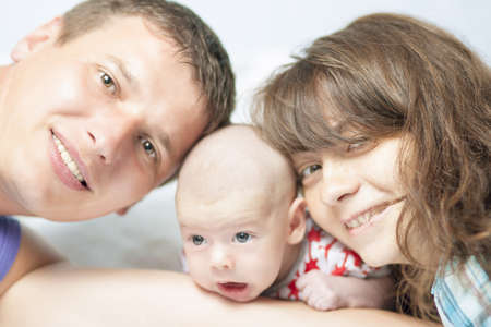 happy family kissing a newborn infant and looking to camera