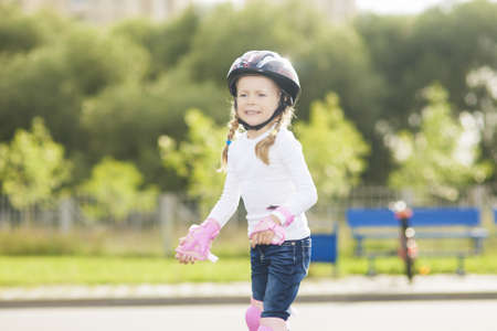 portrait of small little caucasian blond girl skating outside on stadium track in protective helmetの写真素材