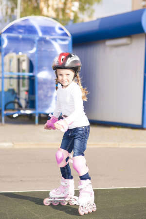 portrait of small little caucasian blond girl skating outside on stadium track in protective helmetの写真素材