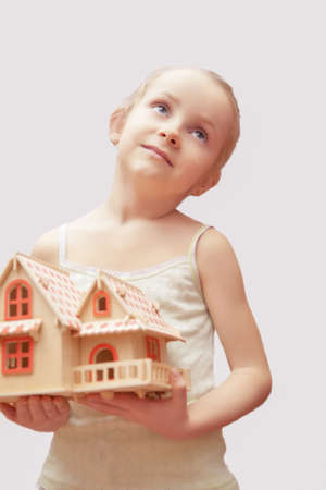portrait of young little girl holding scale house model showing dreaming facial expression. isolatedの写真素材