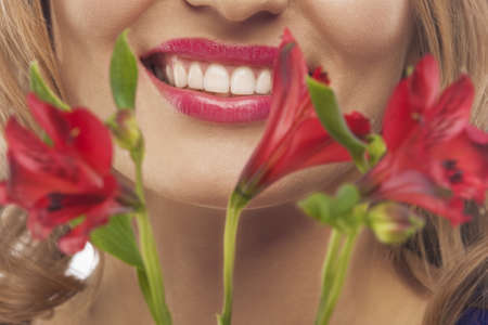 face of young smiling woman with bunch of flowersの写真素材
