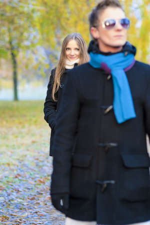 happy looking caucasian couple standing one after another in a row outsideの写真素材