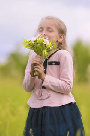 portrait of young little girl smelling flowers with smile on face outsideの写真素材