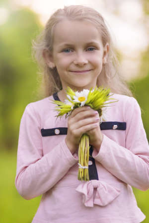 portrait of nice and cute little blond with flowers. vertical shot.の写真素材