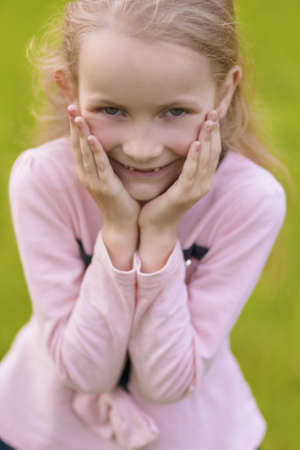 plovely portrait of cute little blond girl showing   positive emotions outside. vertical shot