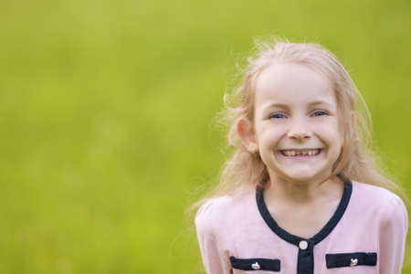 little girl showing happy smile standing outsideの写真素材