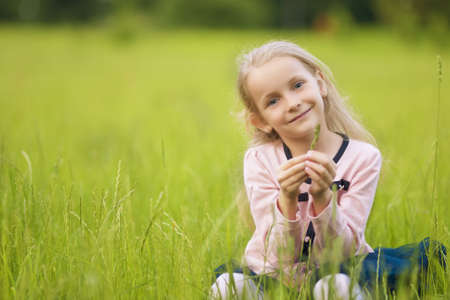 little girl sitting on the grass on lawn outsideの写真素材