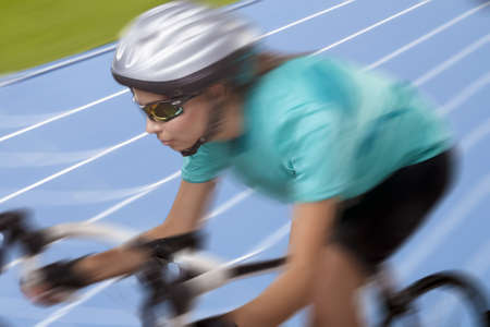 portrait of  woman riding bike on racing track and looking straight forward  model wears  a...