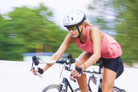 young caucasian female woman riding on the race bike outdoors. panning technique used. horizontal shotの写真素材