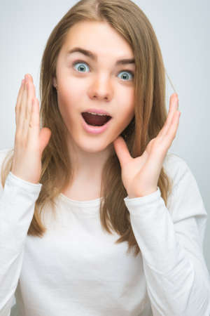 portrait of surprised teenage girl with mouth open  isoalted over gray background  vertical shotの写真素材