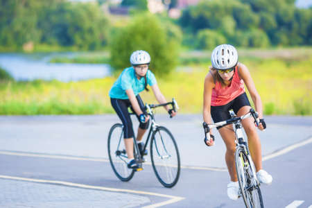 Training cycle  of the two female caucasian sportswomen riding sport bikes outdoors horizontal imageの写真素材