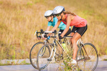 Training cycle  of the two female caucasian sportswomen riding sport bikes outdoors horizontal imageの写真素材