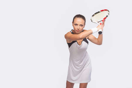 Portrait of Female Tennis Sportswoman In Professional Outfit Preparing to Serve. Isolated Over Pure White. Horizontal Imageの写真素材