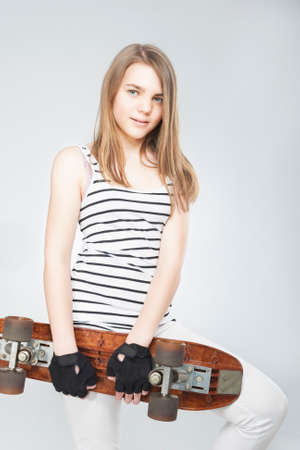 smiling Teenage Girl With Skateboard Over White Background. Vertical Imageの写真素材