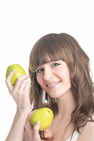 Happy Young Caucasian Girl With Brackets On Teeth Demonstrating Green Apples. Isolated Over White Background. Vertical Imageの写真素材