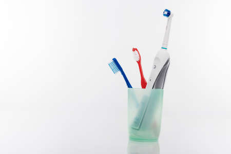 Electric and Manual Toothbrushes in One Cup Together. Isolated Over White Background. Horizontal Imageの写真素材