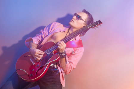 Male Guitarist Playing the Electric Guitar. Shot with Strobes and Halogen Light to Create Mood and...