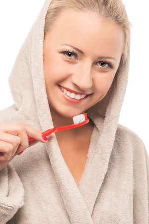 Blond Woman in Dressing Gown Cleaning Teeth with Manual Toothbrush. Over White Background. Vertical Imageの写真素材