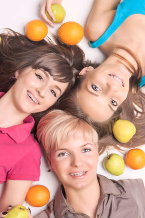 Portrait of Young and Happy Caucasian Girls With Teeth Ortho Braces Having Fun With Lots of Fruits. Vertical Imageの写真素材