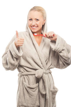 Positive Young Blond Woman With Manual Toothbrush Showing Thumbs up Sign. Isolated Over Pure White Background. Vertical Imageの写真素材