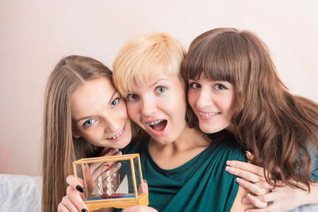 Three Young Caucasian Girls With Teeth Brackets Sitting Together and Smiling. Holding Present. Horizontal Image.の写真素材