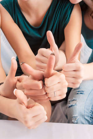 Closeup of Hands of Three Caucasian Females Showing Thumbs Up In Home Environment. Vertical Imageの写真素材