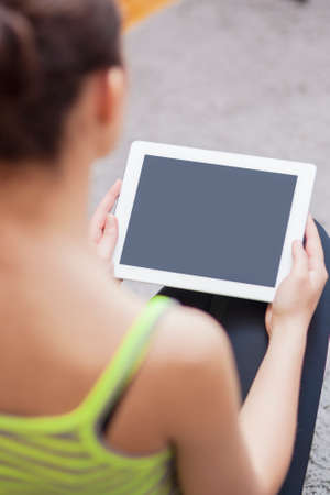 Back View Portrait of Woman Holding Tablet Computer. Focus on Tablet Computer. Vertical Image