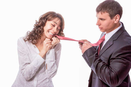 Young Caucasian Couple With Playful Expression. Biting Tie and Draging Forward. Isolated Over Pure White Background. Horizontal Image Compositionの写真素材
