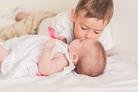 Little Caucasian Boy Kissing His Newborn Sister. Indoors Shot. Horizontal Imageの写真素材