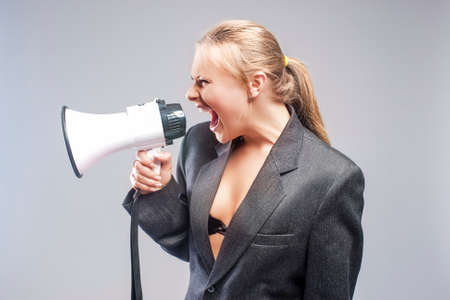Caucasian Blond Woman Shouting Using Megaphone. Against Grey Background. Horizontal Imageの写真素材