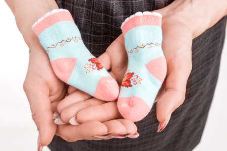 Profile Of Pregnant Woman Holding Baby Small Socks On Hands. Isolated Over White Background. Horizontal Image Compositionの写真素材
