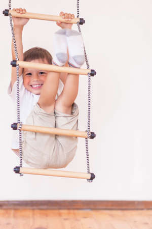Youth Concept: Happy Laughing Caucasian Little Boy Usiing Sport Equpment Indoors. Vertical Image