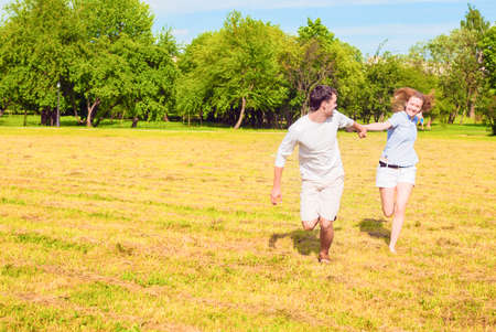 Happy Couple Resting Outdoors and Having Very Good Time Running Together with Hands Connected.Horizontal Imageの写真素材