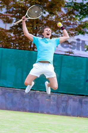 Tennis Sport Concept: Portrait of young Exclaiming Male Caucasian Tennis Player With Raquet Outdoors on Court.Vertical Image Compositionの写真素材
