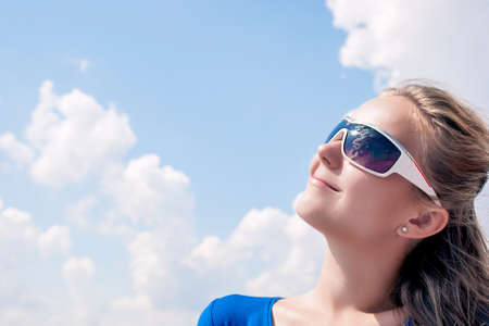 Profile of Young Smiling Caucasian Blond Female Wearing sunglasses and Looking Up. Horizontal Image...