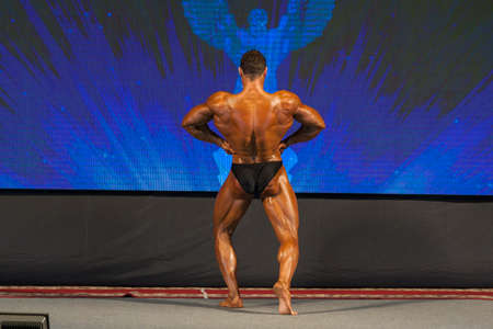 Professional Male Caucasian Bodybuilder Performing on Stage. Back View. Horizontal Image Compositionの写真素材