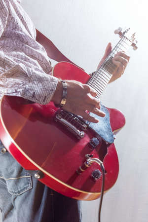 Male Guitar Player Performing with Electric Guitar Hands Closeup. Mixed Light Used. Vertical Image Orientationの写真素材