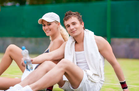 Sport and Fitness Concepts: Happy Caucasian Couple In Tennis Gear Posing On Court During Waterbrake. Horizontal Image Compositionの写真素材