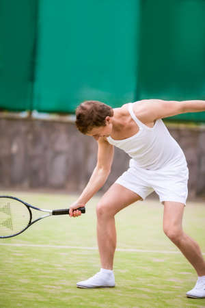 Portrait of Caucasian Handsome Man in Tennis Outfit Posing with Tennis Racquet Outside. Vertical Image Orientationの写真素材