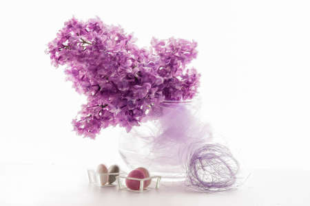 Bouquet of Spring Fresh Lilacs on Vase With Decorative Accessories. Against White. Horizontal Image...