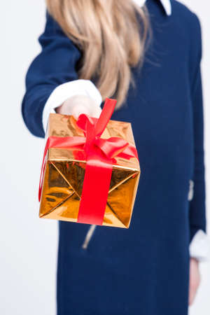 Closeup of Hand of Little Blond Girl Giving Christmas Gift Box Forward. Face is Not Visible....