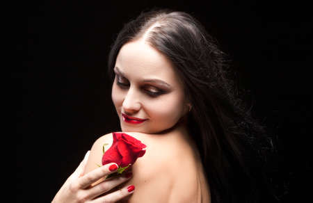 Sexy Sensual Brunette Woman Posing With red Flower in Studio Against Black Background. Horizontal Image Compositionの写真素材