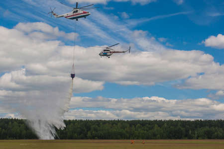 Minsk, Belarus-June 21, 2014: Staff of Ministry of Emergency Situations Spraying Water over Trees on MI-8 and MI-26 Helicopters During Aviation Sport Event Dedicated to the 80th Anniversary of DOSAAF Foundation in Minsk on June 21, 2014 in Minsk, Belarusのeditorial素材