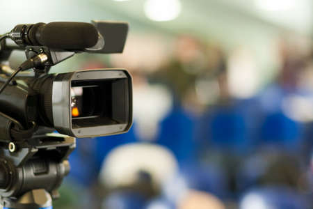 Front View of Professional Videocamera. Positioned Against Blurred Background. Horizontal Image