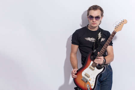 Music Concepts. Portrait of Young and Tranquil Caucasian Guitarist Posing Against White Background....