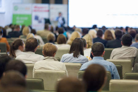 Female Host Speaking in Front of the Large Audience During Business Conference. Horizontal Image