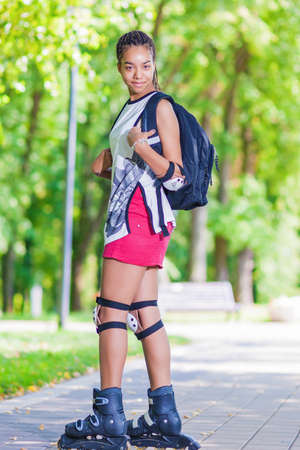 Sport Concepts. Young African American Teenage Girl Posing on Roller Skates Outdoor in Park Area....