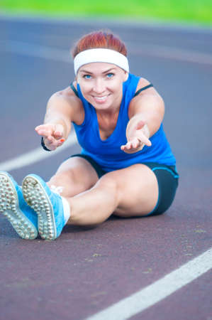 Portrait of Caucasian Female Athlete During Body Stretching Exercises Outdoors. Vertical Shot